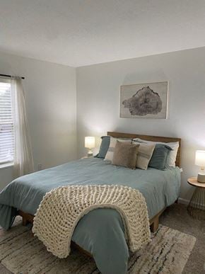 Grove City apartment for rent - A bedroom with a bed covered in a blue comforter and a white knitted throw.