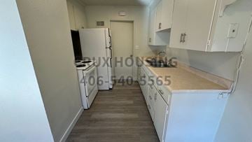 Havre apartment for rent - A kitchen with white cabinets and a wooden countertop.