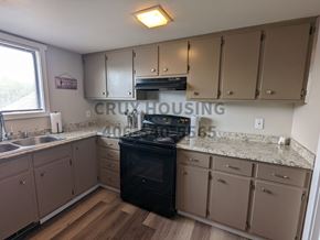 Great Falls apartment for rent - A kitchen with a black stove top oven and beige cabinets.