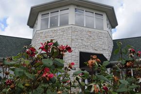 Richwood apartment for rent - A house with a stone tower and a window surrounded by red flowers at The Legends at Steeplechase Apartments, Richwood