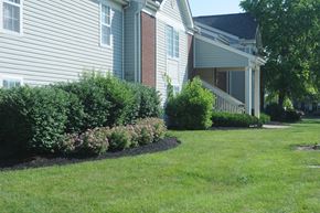 Cincinnati apartment for rent - A house with a well-kept lawn and a flower bed in front.