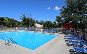 Crescent Springs apartment for rent - A large blue swimming pool surrounded by lounge chairs and umbrellas.