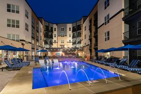 Beachwood apartment for rent - a large swimming pool in front of an apartment building at night at Aster Apartments, Beachwood, OH 44122