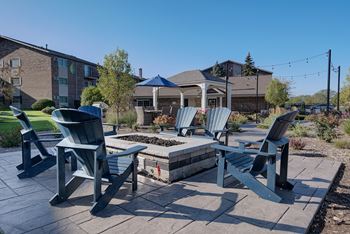A patio with chairs and a table in the foreground with a building in the background