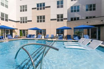 A pool with blue and white chairs and a building in the background