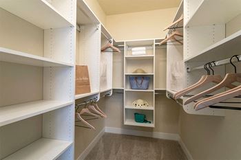 A walk in closet with shelves and shoes