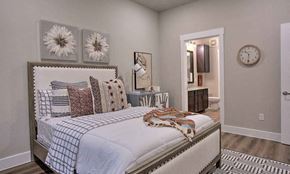 Denton apartment for rent - a bedroom with a bed and a clock on the wall at Hunters Creek Apartments, Denton, TX 76210