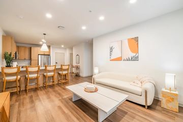 St. Peters apartment for rent - A living room with a white couch, wooden chairs, and a painting on the wall.