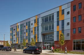 Detroit apartment for rent - A modern building with a glass facade and a red brick building next to it.