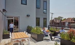 Detroit apartment for rent - Two men are sitting on chairs and talking in a patio area.