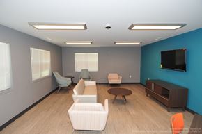 Kalamazoo apartment for rent - A living room with a white couch, a brown coffee table, and a flat screen TV mounted on the wall.