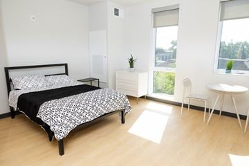 Detroit apartment for rent - A bedroom with a bed, a nightstand, a chair, and a window.