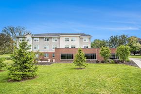 Portage apartment for rent - A large building with a grassy front yard.
