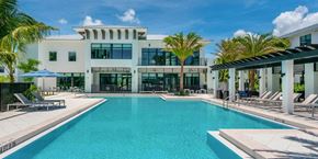 Pembroke Pines apartment for rent - a large swimming pool with chaise lounge chairs and palm trees in front of a white building