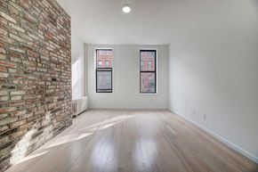 Brooklyn apartment for rent - an empty living room with a brick wall and wood floors
