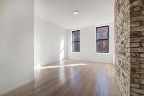 Brooklyn apartment for rent - an empty living room with a brick wall and wood floors