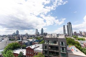 Brooklyn apartment for rent - A cityscape with a mix of modern and older buildings under a partly cloudy sky.