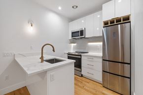 Brooklyn apartment for rent - a kitchen with white cabinets and a stainless steel refrigerator