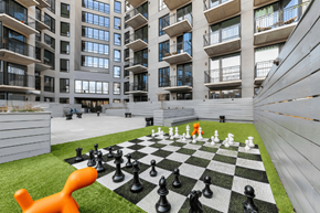Brooklyn apartment for rent - A giant chess board with pieces on a lawn in front of a building.