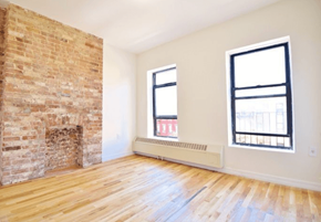New York apartment for rent - A room with a brick fireplace and wooden floors.