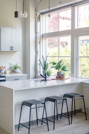 St. Louis apartment for rent - a kitchen with a white counter top and three black stools in front of a window at The 22 Apartments, St. Louis, MO 63103