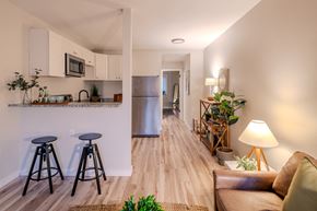 St. Louis apartment for rent - a living room with stools and a kitchen with a refrigerator