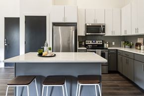 Saint Louis apartment for rent - a kitchen with stainless steel appliances and a white island with three stools
