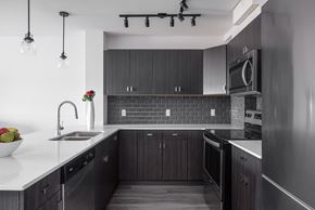 Ft Mcmurray apartment for rent - a kitchen with dark wood cabinets and a white counter top