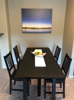 Ft Mcmurray apartment for rent - A black dining table with a bowl of fruit on it and four chairs.
