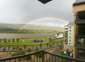 Ft Mcmurray apartment for rent - A rainbow appears over a lake with a building and playground in the foreground.