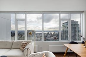 North Vancouver apartment for rent - A modern living room with a view of the cityscape outside the large window.