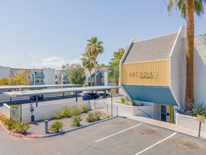 Phoenix apartment for rent - a parking lot with a yellow and blue building with the words arcadia on it