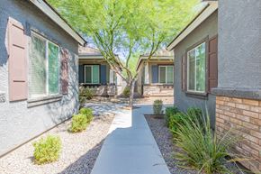 Peoria apartment for rent - a walkway between two houses with trees and plants at Villas on Olive, Peoria, AZ 85345