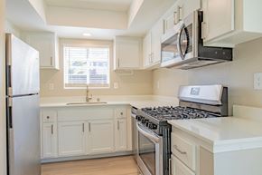 Oceanside apartment for rent - a kitchen with white cabinets and a stove and a refrigerator