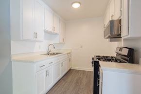 Reseda apartment for rent - a kitchen with white cabinets and a stove and a sink
