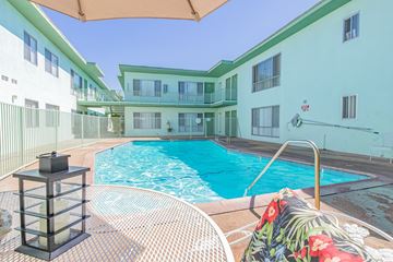 Panorama City apartment for rent - A pool surrounded by a white fence and a chair with a floral cushion.
