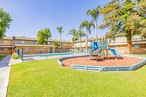 Bakersfield apartment for rent - a playground with a blue playset in the grass