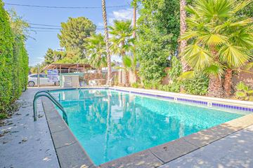 Sherman Oaks apartment for rent - A pool surrounded by greenery and palm trees.
