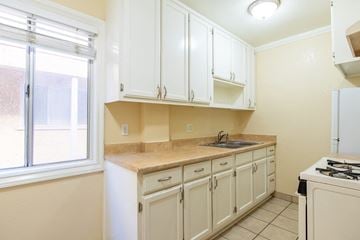 Long Beach apartment for rent - A kitchen with white cabinets and a beige countertop.