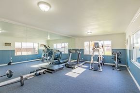 Buena Park apartment for rent - A spacious gym with a variety of equipment including treadmills, weight machines, and a bench press.