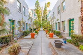 Long Beach apartment for rent - A row of potted plants line a walkway between two buildings.