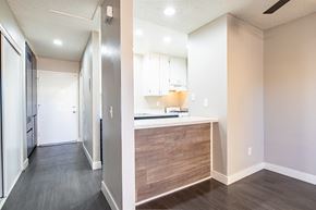 Moreno Valley apartment for rent - a renovated kitchen with white cabinets and wood flooring and a hallway with a door