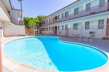 Reseda apartment for rent - A blue swimming pool in front of a building.