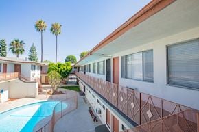 Reseda apartment for rent - a balcony with a pool and a building with palm trees