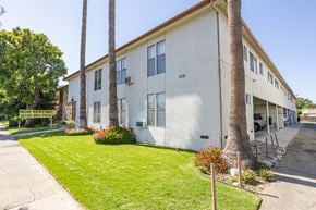Reseda apartment for rent - a white building with a green lawn and palm trees