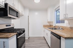 Canoga Park apartment for rent - A kitchen with white cabinets and a black stove top oven.