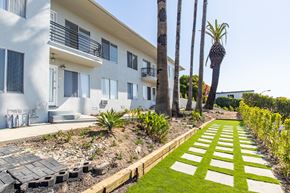 Malibu apartment for rent - A white building with a balcony and a palm tree in front.