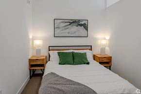 Minneapolis apartment for rent - a bedroom with a bed with green pillows and a painting on the wall