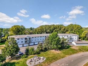 Woodbury apartment for rent - A large white building surrounded by trees and a circular garden in front.