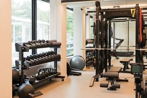 Minneapolis apartment for rent - A gym with a variety of equipment including a squat rack, bench, and dumbbells.